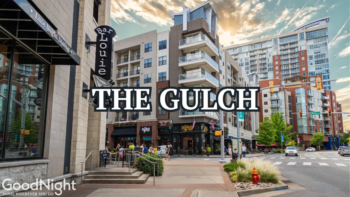 A bustling street scene in The Gulch neighborhood showcases Bar Louie, modern apartments, and pedestrians enjoying city life. Outdoor dining and vibrant signage emphasize the area's accessibility, dining options, and the lively urban energy just a short drive away.