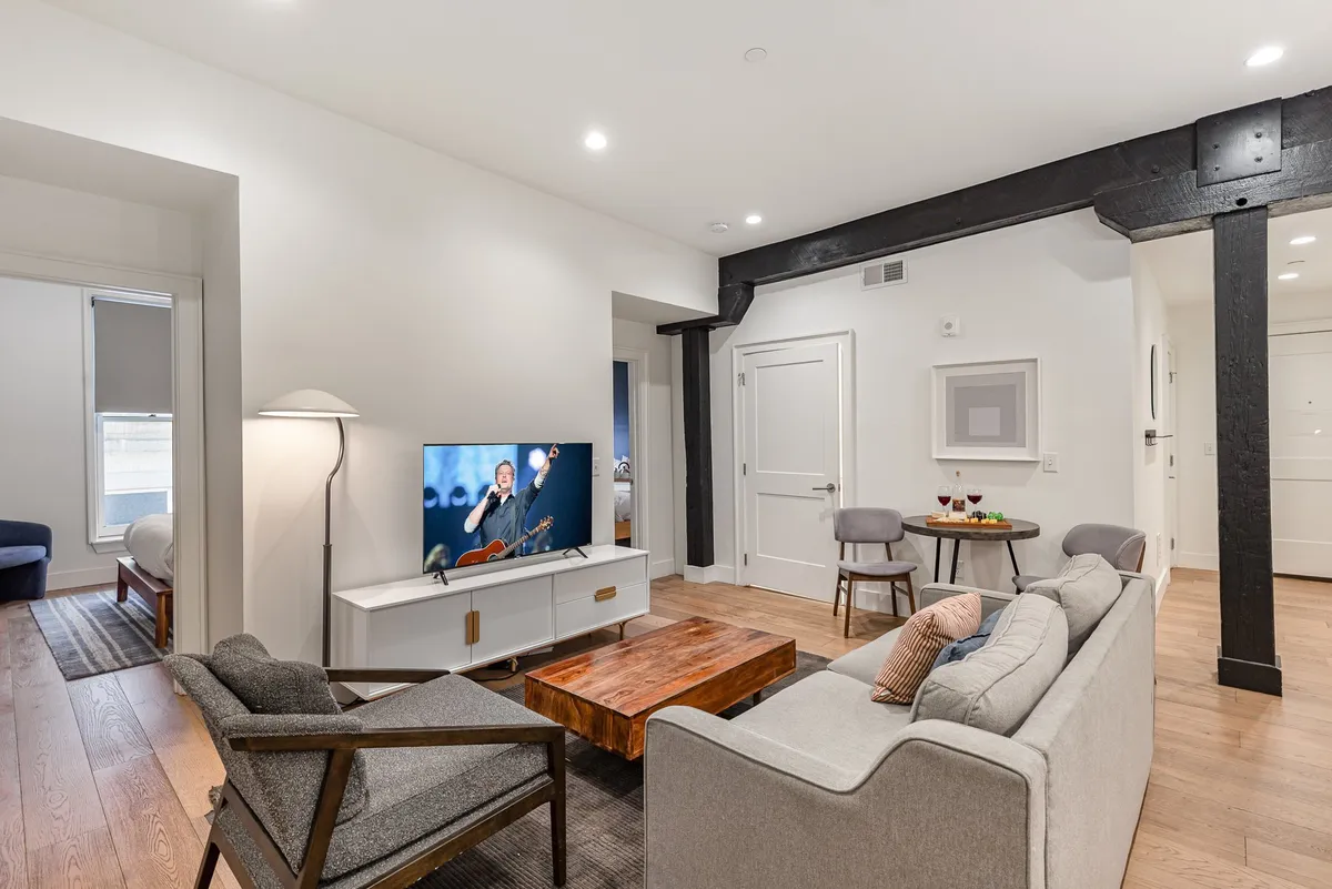 A modern, inviting living room with a comfortable sofa, coffee table, television, and accent chairs arranged for relaxation. The space is ideal for unwinding, with the sofa doubling as a sleeper for spontaneous guests, as referenced in the section.